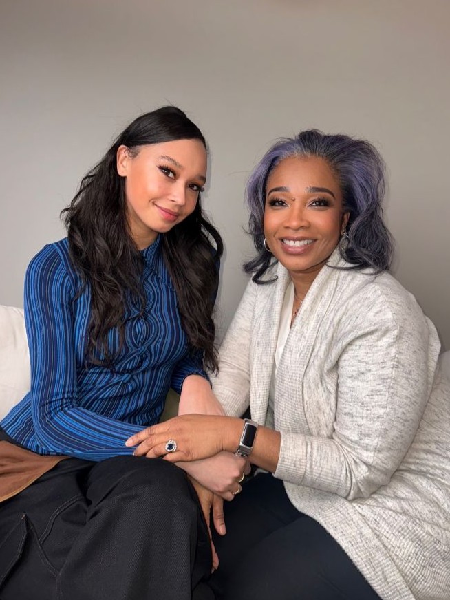 Two women sitting side-by-side, smiling at the camera.